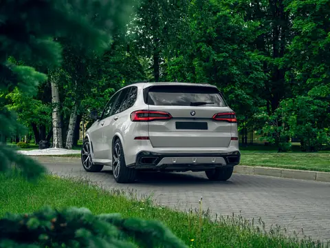 A white SUV on a quiet road between trees