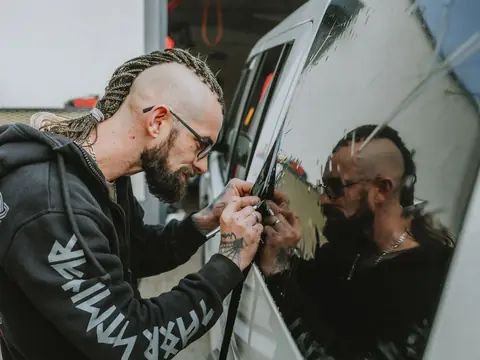 An installer working a squeegee along a car's side window