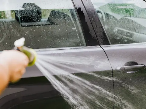 Water running down the side windows of a dark car