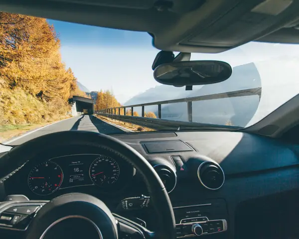 The road ahead through a wide, clean windshield, the mirror at the top of the glass
