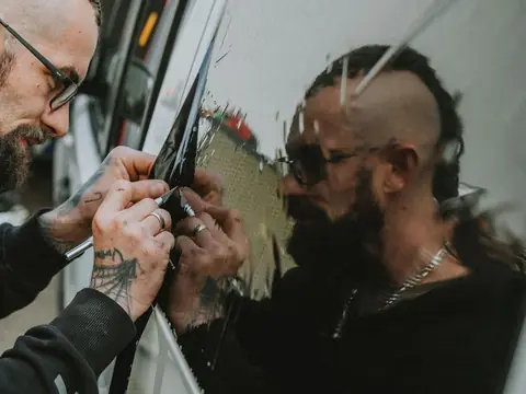 Hands pressing a squeegee along the edge of a side window