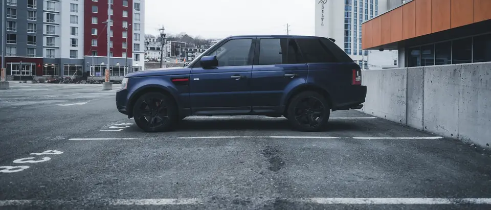 A blue SUV parked in an empty city lot